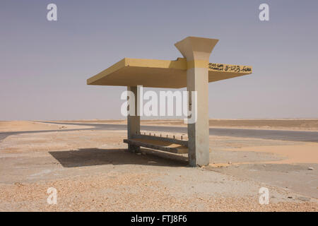 A remote bus shelter in a desolate desert landscape near Bagdad, Kharga Oasis, Western Desert, Egypt. The desert lies in the New Valley Governorate, 350 km (220 mi.) and measures approximately 80 km (50 mi) from east to west and 25 km (16 mi) from north to south and is patrolled by armed police convoys. Stock Photo