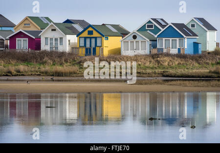 A Row of Beach Huts and their Reflections in a Lagoon of Christchurch Harbour at Hengistbury Head, Bournemouth, Dorset, England, UK Stock Photo