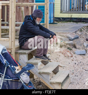 A mature man sitting on steps in a thoughtful mode with his dog, Jack Russell Terrier, alongside. Stock Photo