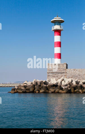 Red and white striped lighthouse tower standing on the entrance pier in port of Burgas, Black Sea coast, Bulgaria Stock Photo