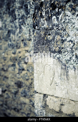 Carved love heart on a cotswold stone wall. Bibury, Gloucestershire, England. Applied Vintage filter Stock Photo
