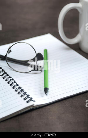 Close up shot of an open book with reading glasses and a cup of coffee. Stock Photo