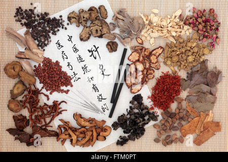 Chinese medicinal herb ingredients, acupuncture needles and moxa sticks  with calligraphy on rice paper. Stock Photo