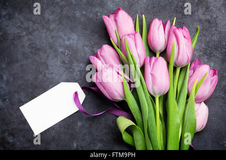 Fresh purple tulip flowers with tag label on dark stone table. Top view with copy space Stock Photo