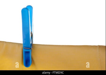Blue plastic clothes peg or pin securing a yellow t-shirt on clothes line. Stock Photo