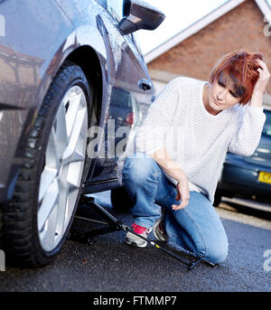 Woman changing wheel on her car Stock Photo