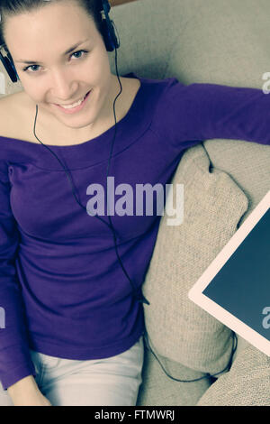 Young woman using digital tablet at home relaxing in sofa Stock Photo