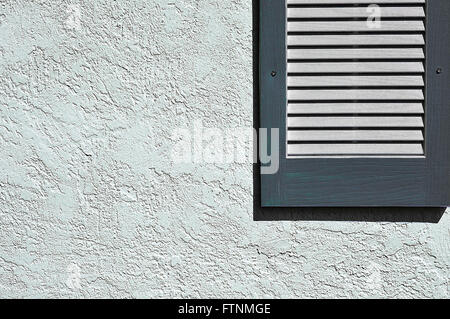 Slate Blue Shutter on Exterior Stucco Wall Stock Photo