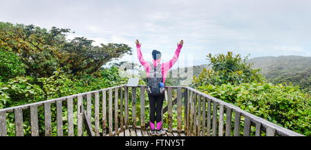 female hiker raising hands over a viewpoint Stock Photo