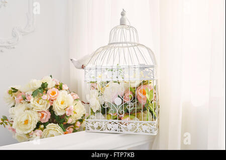 Decorative bird cage with bouquet of flowers in the interior Stock Photo