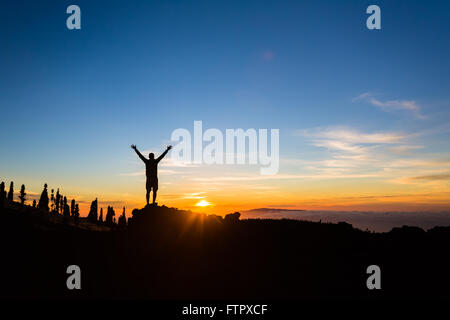 Man hiker silhouette with arms outstretched in mountains. Male runner or climber looking at sunset view. Business concept Stock Photo