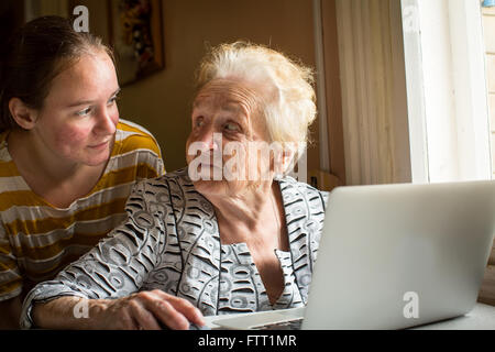 Young girl teaches her grandmother to use a computer. Stock Photo