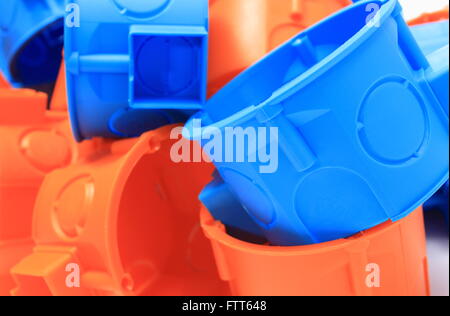 Heap of blue and orange plastic electrical boxes, components for electrical installations, accessories for engineering jobs Stock Photo