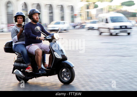 A couple ride a Vespa scooter on the street in Rome, Italy. Vespa scooter is an italian symmbol. Stock Photo
