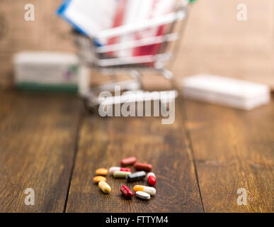 Colorful pills,capsules,pill box and shopping cart on dark wooden background Stock Photo