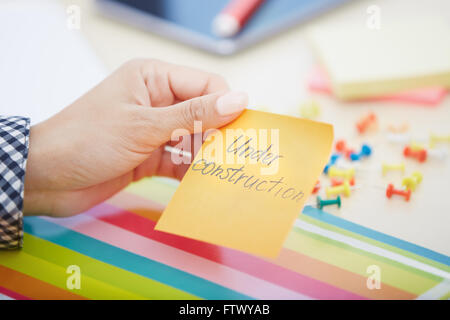 Human hand holding adhesive note with Under construction text Stock Photo