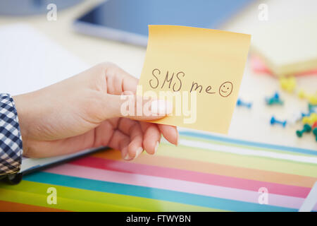 Human hand holding adhesive note with SMS me text Stock Photo