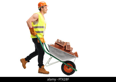 Construction worker pushing a wheelbarrow full of bricks isolated on white background Stock Photo
