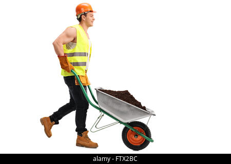 Construction worker pushing a wheelbarrow with a pile of dirt in it isolated on white background Stock Photo