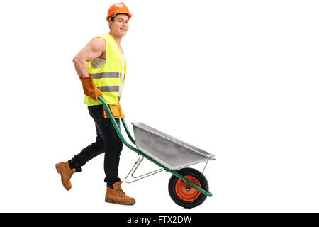 Young construction worker pushing an empty wheelbarrow and looking at the camera isolated on white background Stock Photo