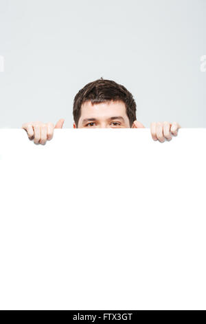 Man peeking from blank board isolated on a white background Stock Photo