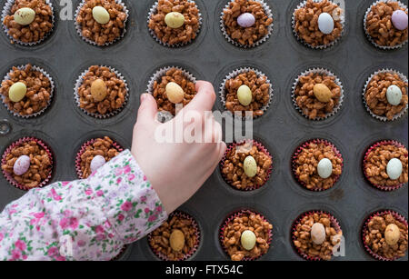A childs hand selecting an Easter chocolate krispy cake Stock Photo