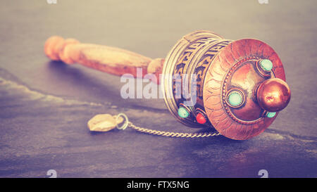 Vintage stylized old Tibetan prayer wheel used to accumulate wisdom and good karma and to purify bad karma, shallow depth of fie Stock Photo