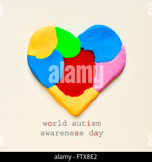 the text world autism awareness day and a heart made from modelling clay of different colors on an off-white background Stock Photo