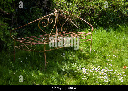 Old garden furniture made from iron etc sitting in an overgrown garden. Stock Photo