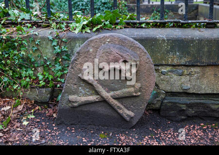 A close-up of a Skull and Crossbones on a headstone in a graveyard. Stock Photo