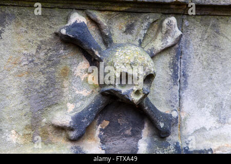 A close-up of a skull and crossbones on a headstone in a graveyard. Stock Photo