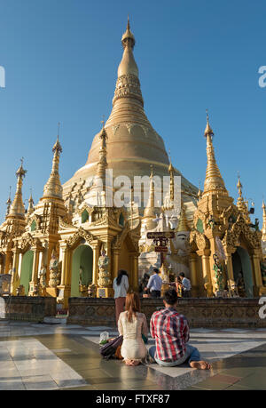 Young couple prays at Shwedagon Pagoda, Yangon (Rangoon), Myanmar (Burma) Stock Photo