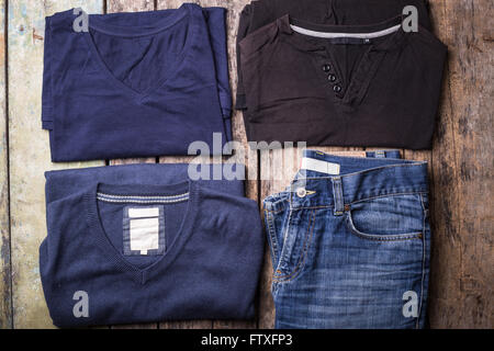 Various Man clothes collected on wooden background. Collection of men's T-shirts, jumper and jeans with blank labels Stock Photo