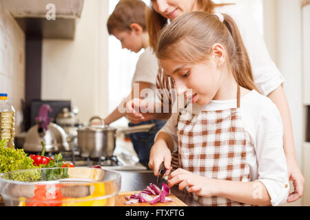 Family cooking background. Mum and daughter cutting onion for salad in the kitchen Stock Photo