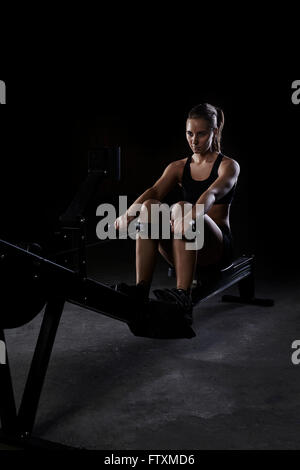Young woman on rowing machine in gym Stock Photo