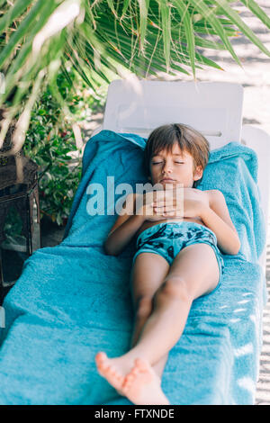 Boy sleeping on a sun lounger on beach