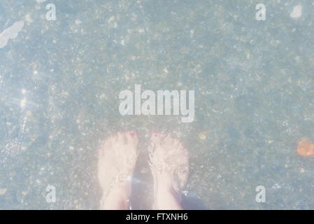 Woman's feet standing in sea Stock Photo