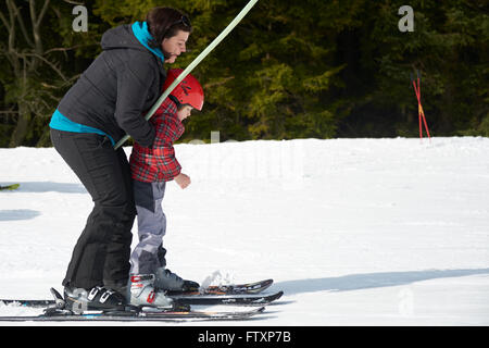 Child skiing in the mountains. Toddler kid in ski suit and safety helmet learning to ski. Kids ski lesson in alpine school. Stock Photo