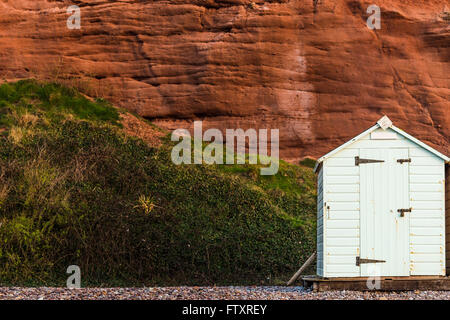 Beach hut row in pastel colors, red rock background, South Devon, UK Stock Photo