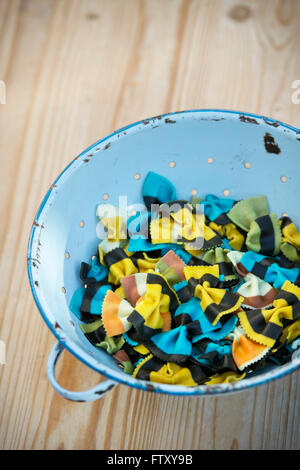 Butterfly Fantasia pasta. Farfalle pasta. Flavored coloured Pasta. Cooked Specialty pasta in a blue retro colander Stock Photo