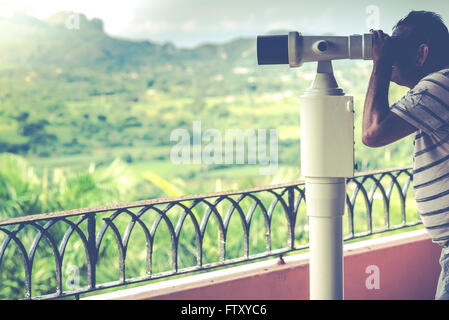 Man looking on mountains with binoculars, vintage toned photo Stock Photo