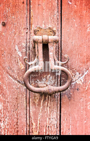 Old vintage door knocker on an old red wooden door Stock Photo