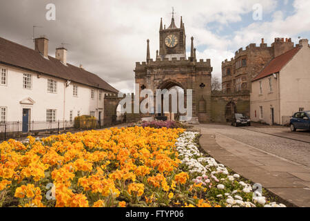 Entrance to Auckland Castle in Bishop Auckland,Co.Durham,England,UK showing the bright yellow flowers and blue moody skies Stock Photo