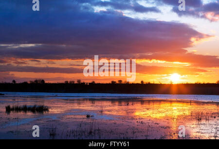 Sunset, Marshside, Southport, Merseyside, UK. 30th March 2016.  After strong blustery winds & snow overnight, a calm spring sunset brings the day to a close over flooded marshland and nature reserve in the town close to the shore.  Credit:  Cernan Elias/Alamy Live News Stock Photo