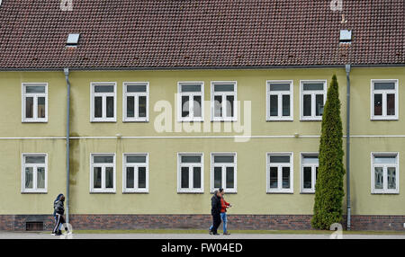 Bad Fallingbostel, Germany. 30th Mar, 2016. Refugees walk past accommodations at the Camp Bad Fallingbostel West refugee accommodation in Bad Fallingbostel, Germany, 30 March 2016. Around 200 are currently being housed in Camp West. Photo: HOLGER HOLLEMANN/dpa/Alamy Live News Stock Photo