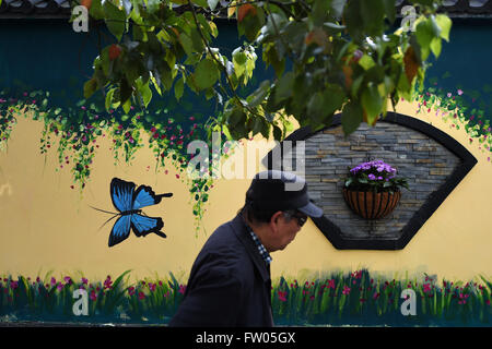 Hangzhou, China's Zhejiang Province. 31st Mar, 2016. A pedestrian walks past a wall with a butterfly pattern in Hangzhou, east China's Zhejiang Province, March 31, 2016. External walls of some buildings along the Miduqiao Road in Gongshu District of the city were painted decorative patterns. © Huang Zongzhi/Xinhua/Alamy Live News Stock Photo