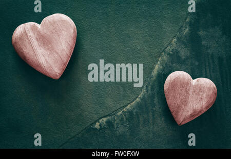 Retro stylized two wooden hearts on cracked stone background, copy space. Stock Photo