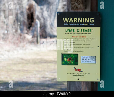 Deer Tick Warning Sign posted in a nature park in New York State. Stock Photo