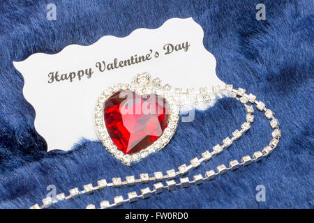 Red jewelry necklace with message on Valentine's card isolated on blue cloth background Stock Photo