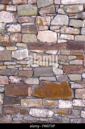 Detail of an old stone wall with stones in different colors, shapes and sizes. Taken in vertical format. Stock Photo